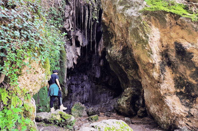 Túrázó a Kremiotis vízesés barlangszerű sziklafala alatt Kritou Terra Ciprus