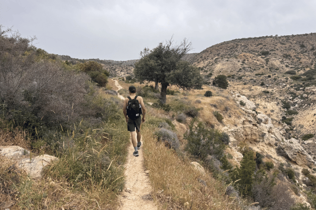 Túrázó a Cape Aspro ösvényén Pissouri közelében, száraz domboldalak és vadregényes ciprusi táj között