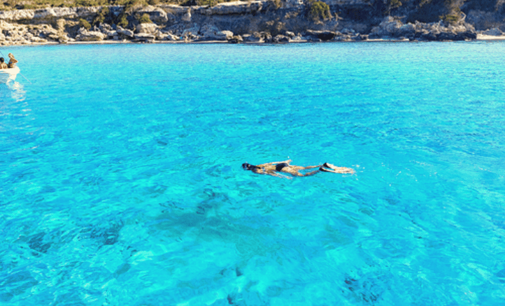 Blue Lagoon az Akamas-félszigeten, kristálytiszta türkizkék vízzel, úszó emberrel.